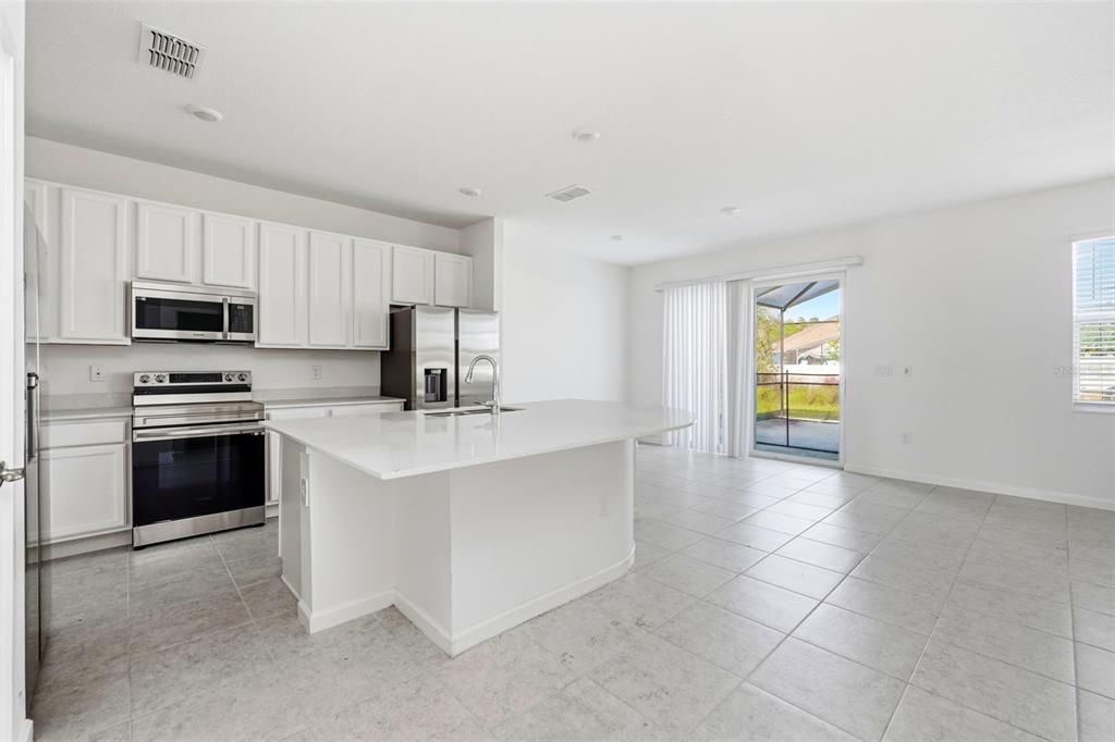 4483 Monado Drive Kissimmee, FL 34746 - Photo 5 of 43 a kitchen with kitchen island granite countertop a stove a sink and a microwave