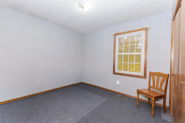 an empty room with a chair and a window