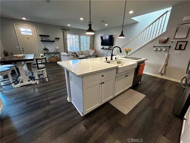 a kitchen with stainless steel appliances kitchen island granite countertop a refrigerator sink and white cabinets