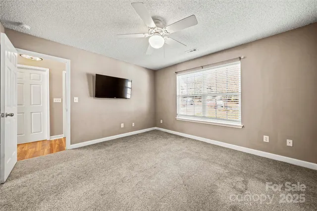 an empty room with windows and ceiling fan