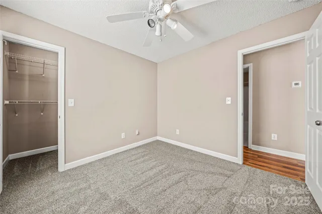 an empty room with closet and chandelier fan