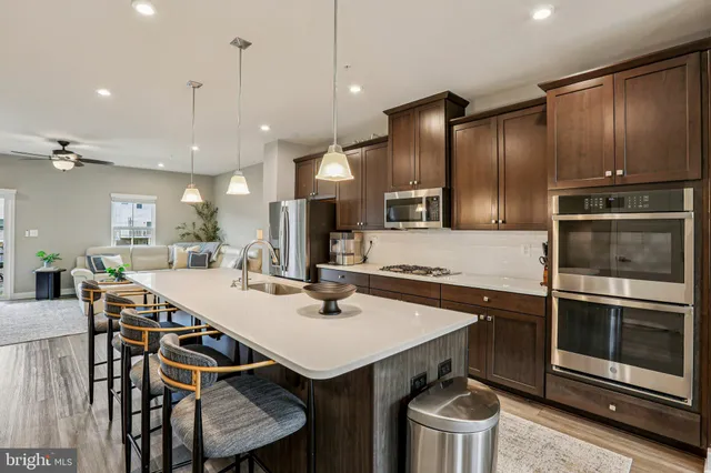 a kitchen with stainless steel appliances a stove a sink a microwave a refrigerator and chairs