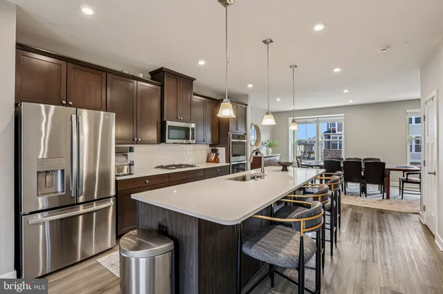 a kitchen with stainless steel appliances a dining table chairs stove and refrigerator