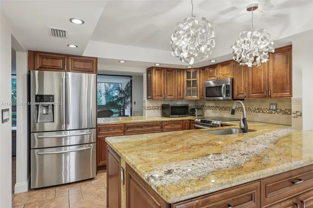 a kitchen with stainless steel appliances granite countertop a refrigerator a stove and a sink with cabinets