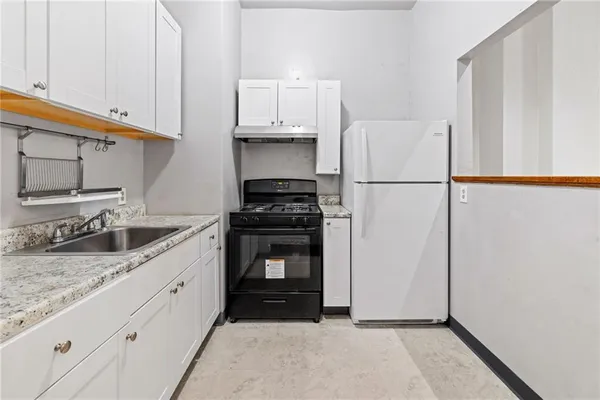 a kitchen with granite countertop a sink a stove and refrigerator