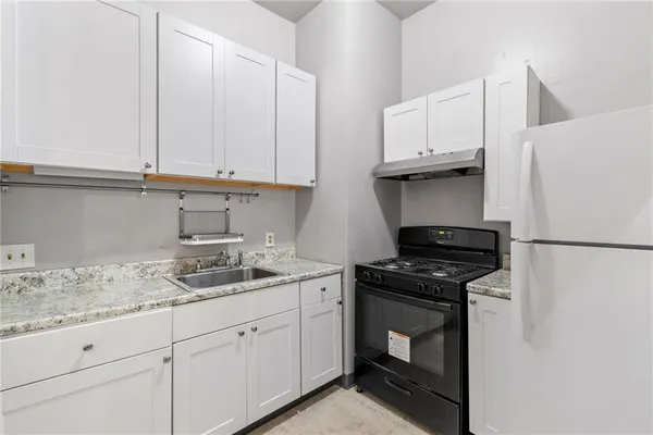 a kitchen with granite countertop white cabinets and white appliances
