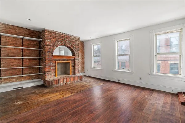 wooden floor fireplace and windows in an empty room