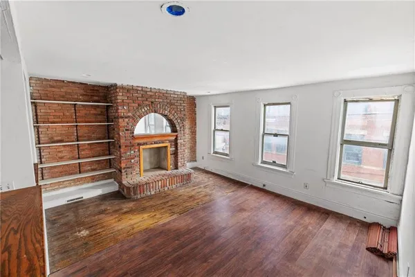 an empty room with wooden floor cabinet and windows