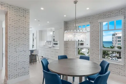 a kitchen with stainless steel appliances kitchen island granite countertop a dining table chairs and white cabinets