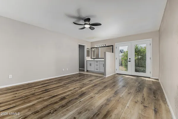 a view of empty room with wooden floor and fan