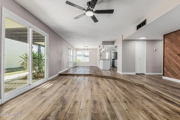 a view of an empty room with wooden floor and a window
