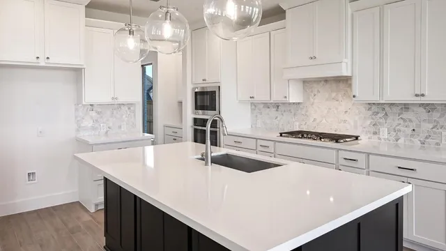a kitchen with stainless steel appliances granite countertop a sink dishwasher and white cabinets with wooden floor