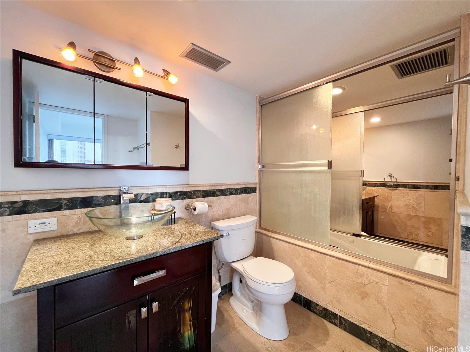 419 Atkinson Drive, Unit 1205 Honolulu, HI 96814 - Photo 7 of 15 a bathroom with a granite countertop sink a mirror and a toilet