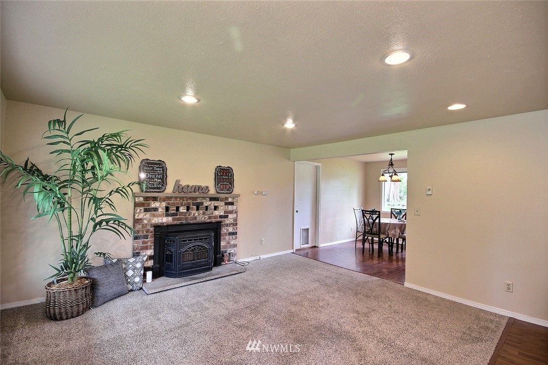 7308 Vandermark Road East Bonney Lake, WA 98391 - Photo 3 of 30 a living room with furniture a fireplace and a potted plant