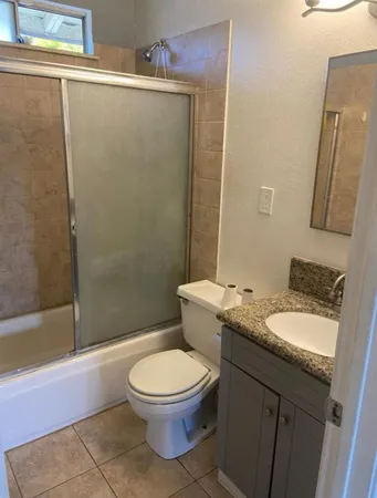 a bathroom with a granite countertop toilet a sink and a mirror