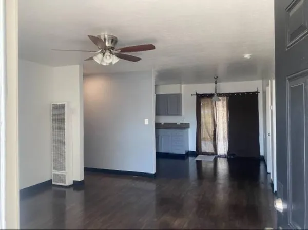 a view of a livingroom with wooden floor a ceiling fan and staircase