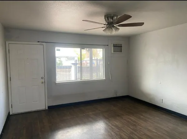 an empty room with wooden floor fan and windows