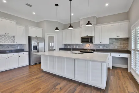 a large kitchen with hardwood floor a sink stainless steel appliances and cabinets