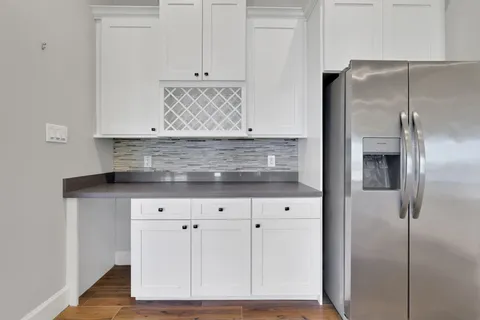 a kitchen with stainless steel appliances granite countertop a stove a sink a microwave a refrigerator and white cabinets with wooden floor