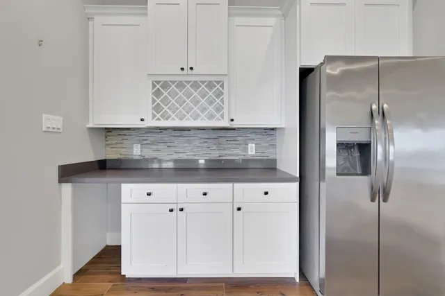 a kitchen with stainless steel appliances granite countertop a stove a sink a microwave a refrigerator and white cabinets with wooden floor