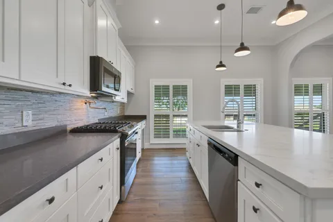 a kitchen with stainless steel appliances granite countertop a stove a sink and a refrigerator