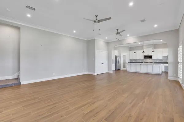 a kitchen with stainless steel appliances granite countertop a stove a sink a microwave a refrigerator and white cabinets with wooden floor