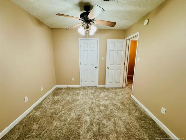 an empty room with a chandelier fan and closet