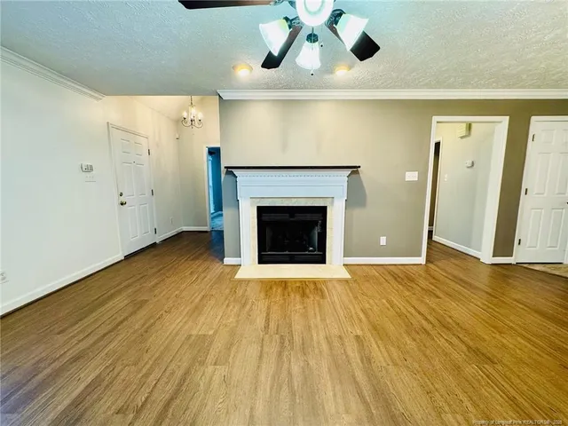 a view of an empty room with wooden floor and a fireplace