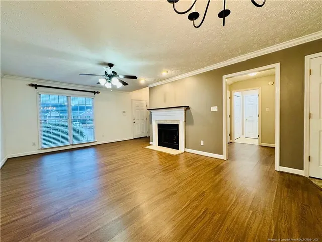 an empty room with wooden floor chandelier and windows