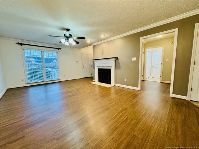 a view of an empty room with wooden floor and a fireplace
