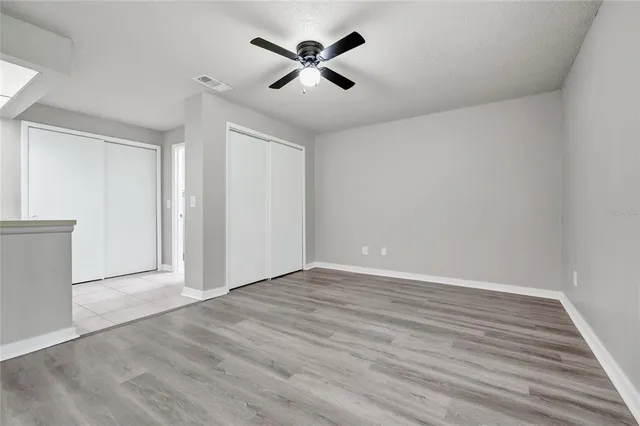 an empty room with wooden floor and ceiling fan
