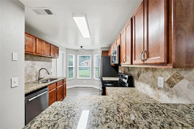 a kitchen with granite countertop a stove a sink and a microwave oven with cabinets