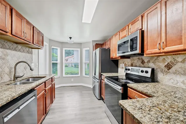 a kitchen with stainless steel appliances granite countertop a stove a sink and a microwave