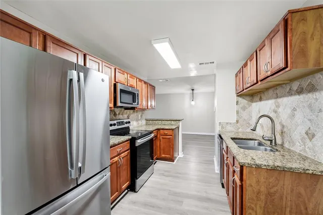 a kitchen with stainless steel appliances granite countertop a refrigerator and a sink