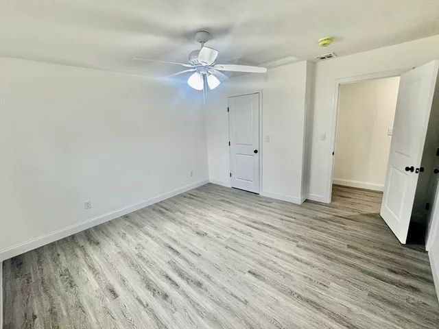 an empty room with wooden floor and fan