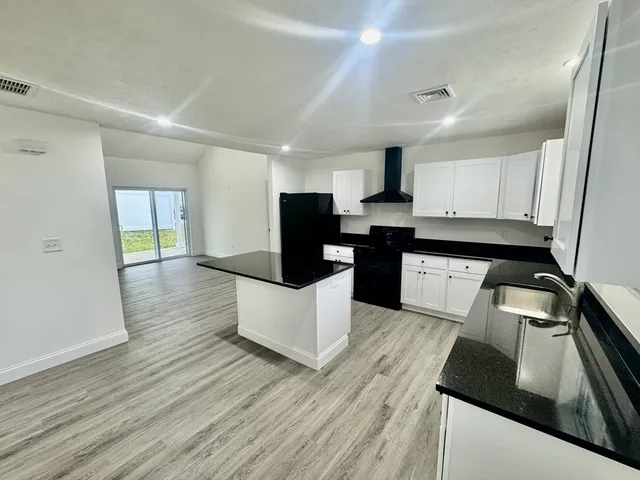 a large kitchen with stainless steel appliances kitchen island granite countertop a stove a sink and a refrigerator