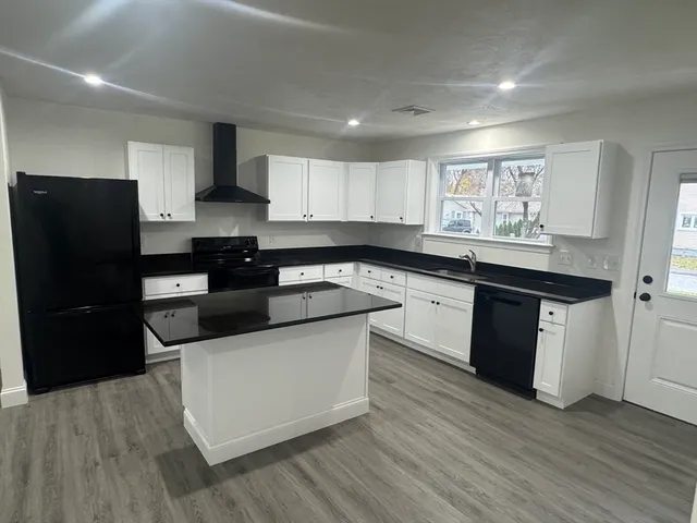 a kitchen with granite countertop a refrigerator sink and wooden cabinets
