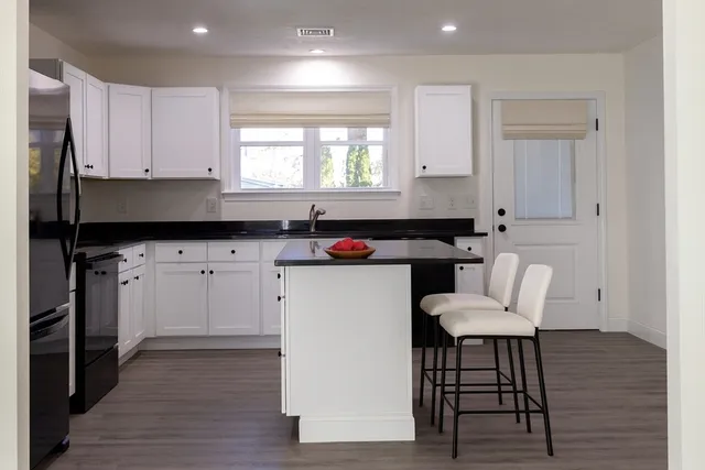 a kitchen with granite countertop a sink cabinets and wooden floor