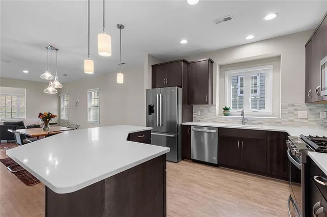 a large kitchen with kitchen island a large counter top stainless steel appliances and cabinets