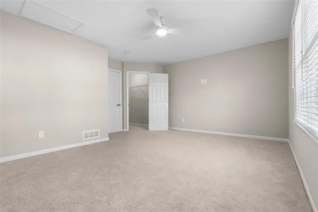 an empty room with windows and chandelier fan