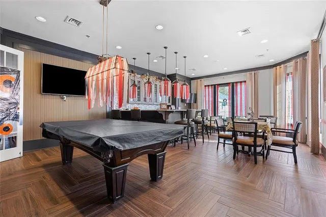 a kitchen with stainless steel appliances granite countertop a stove a refrigerator a kitchen island a dining table and chairs with wooden floor