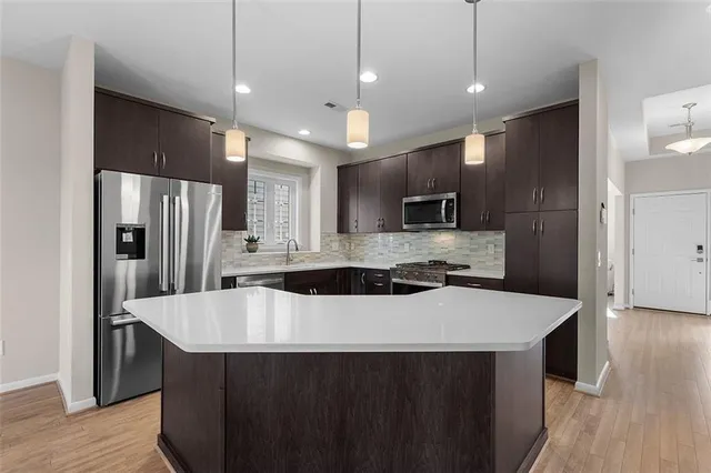 a kitchen with kitchen island a sink stainless steel appliances and wooden floor