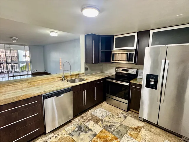 a kitchen with stainless steel appliances granite countertop a refrigerator and a stove top oven