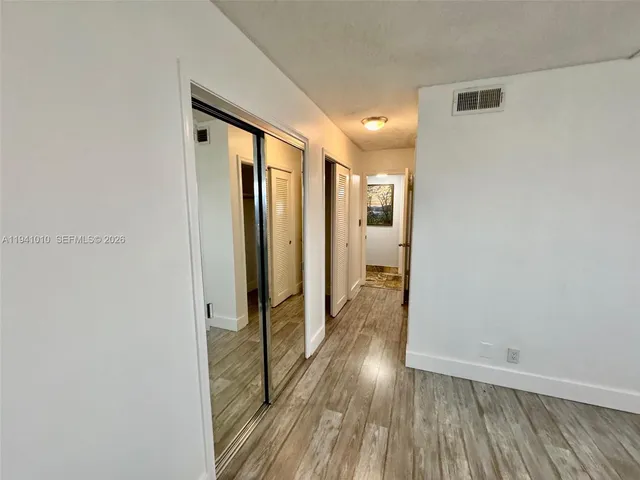 a view of a hallway with wooden floor and staircase