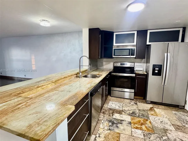 a kitchen with granite countertop a refrigerator stove and sink
