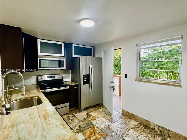a kitchen with stainless steel appliances kitchen island granite countertop a refrigerator and a sink