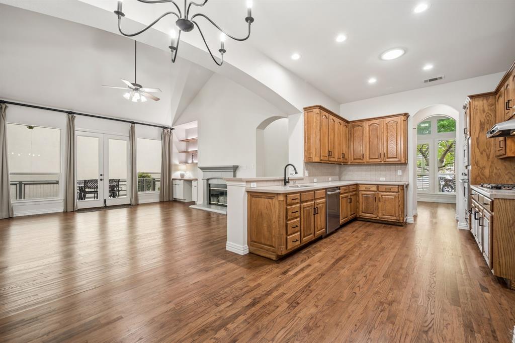 3309 Ricci Lane Irving, TX 75062 - Photo 35 of 36 Kitchen with open floor plan, arched walkways, light countertops, a glass covered fireplace, and hardwood floors