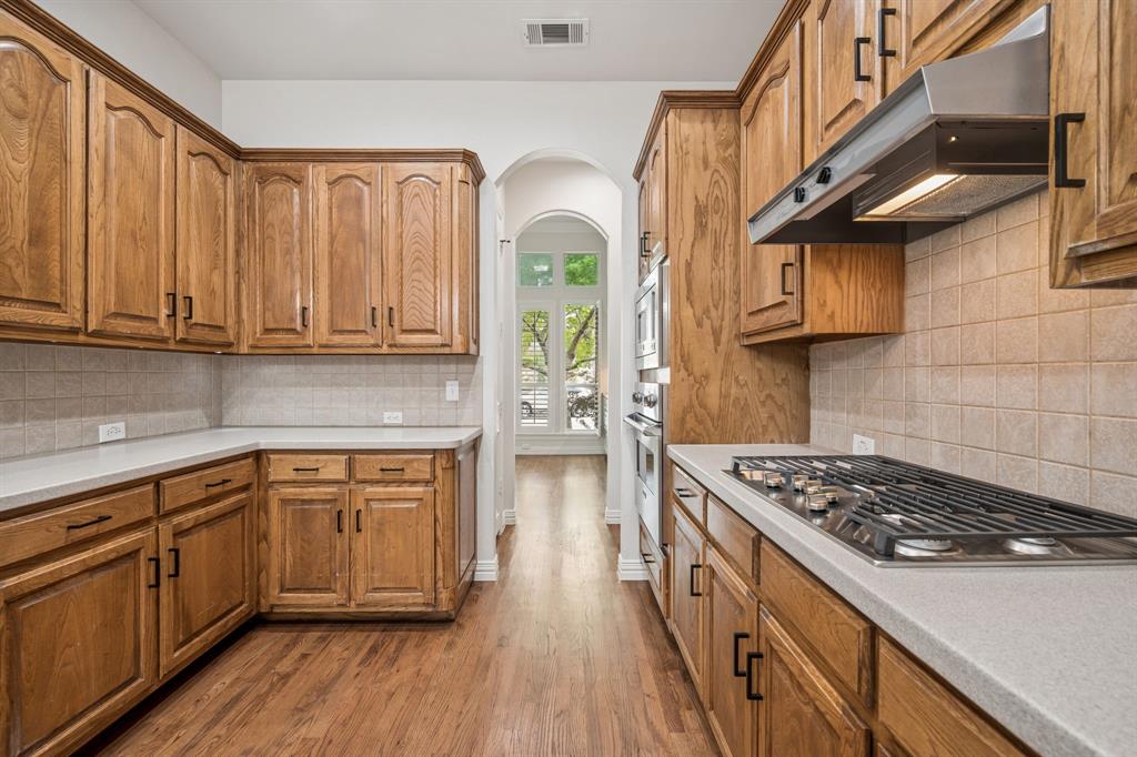 3309 Ricci Lane Irving, TX 75062 - Photo 13 of 36 Kitchen with oak cabinets, hardwood floors, stainless steel appliances, and decorative backsplash
