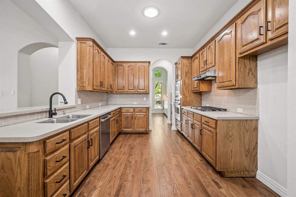 3309 Ricci Lane Irving, TX 75062 - Photo 14 of 36 Kitchen with arched walkways countertops, wood finish cabinetry, and stainless steel appliances