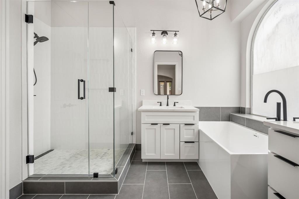 3309 Ricci Lane Irving, TX 75062 - Photo 18 of 36 Bathroom featuring a soaking tub, a stall shower, two vanities, and dark tile patterned flooring